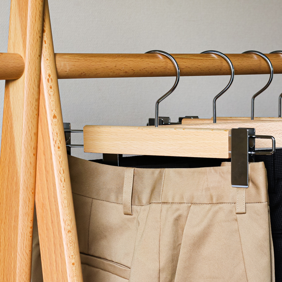 木製パンツハンガーにベージュのパンツを吊るした様子