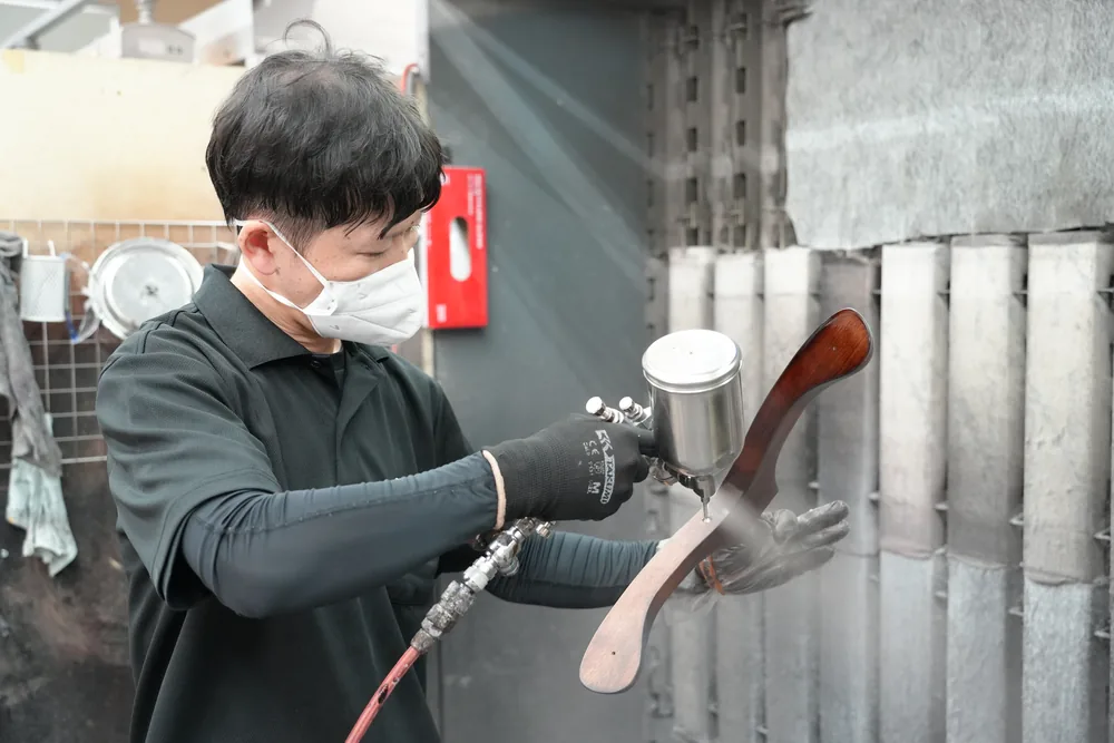 The finishing process: applying color to the wooden parts with a spray gun