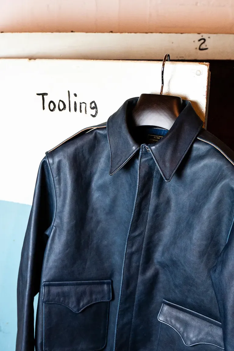 白い背景に映える、ハンガーにかけられたブルーのレザージャケット