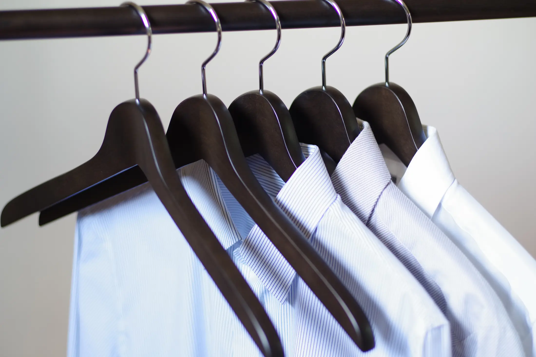 ナカタハンガー製木製ハンガーに掛けられた複数の青いシャツが並ぶ、クローゼットの様子
