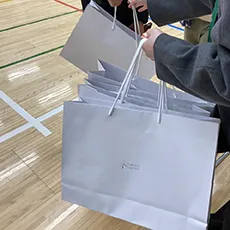 ロゴの入った白い手提げ袋が複数写っている写真