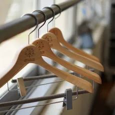 オリジナルのロゴが入った木製ハンガーが並んでかけられている写真