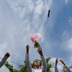 空に向かって卒業証書や花束を投げる生徒たちの写真