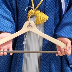 卒業袴姿で木製ハンガーを持つ生徒の写真